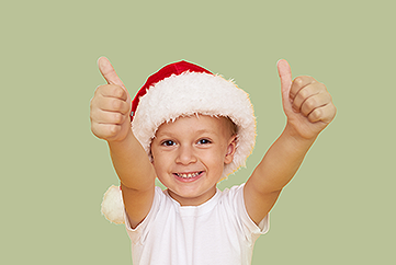 Child wearing Santa hat and giving two thumbs up